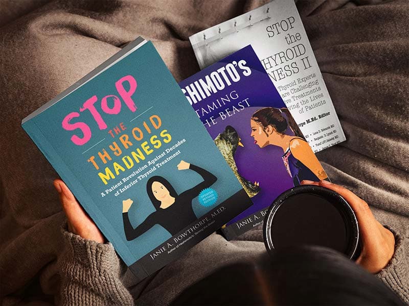 Looking down at someone with three books in their lap, each displaying part of the book covers